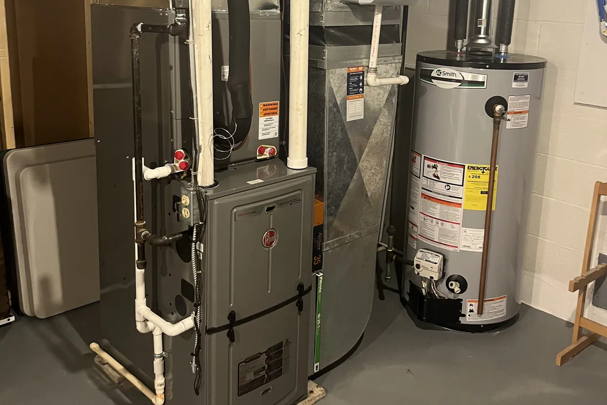 High-efficiency gas furnace with PVC venting next to a water heater in a basement